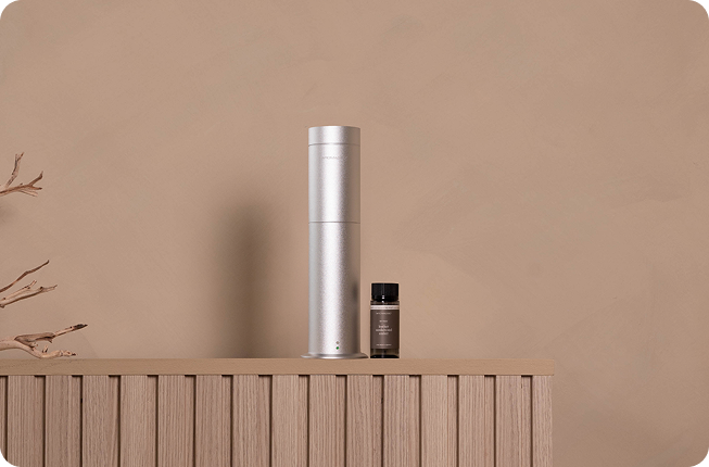 Aroma360 diffuser and oil bottle displayed on a wood console